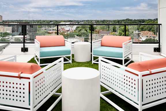 A white chair with orange cushion is placed on a balcony.