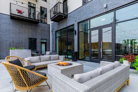 A patio with a couch, chairs, and a table with a fire pit.