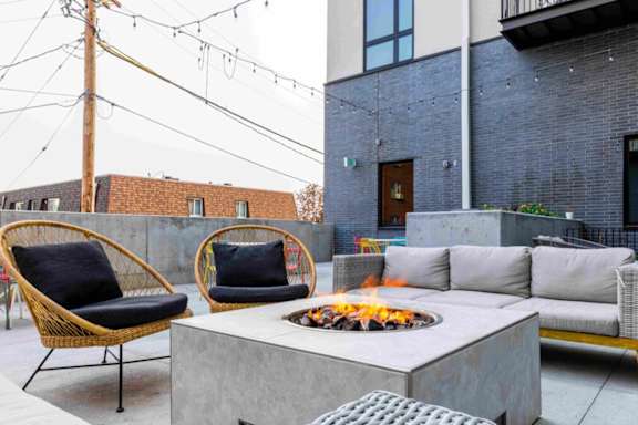 A patio with a fire pit and chairs.