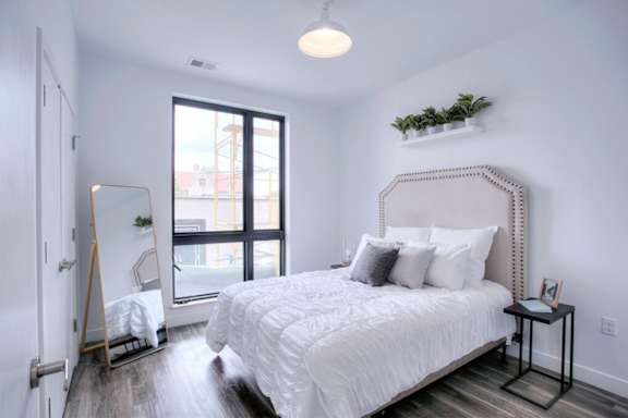 A bedroom with a large bed and a window overlooking a cityscape.