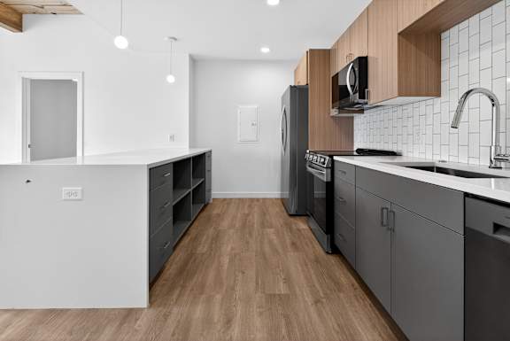 A modern kitchen with wooden floors and grey cabinets.