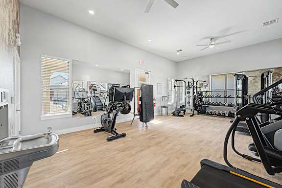 A gym with a variety of equipment including treadmills, weights, and exercise machines.
