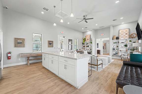 A well-lit, spacious kitchen and dining area with white cabinetry and a wooden floor.