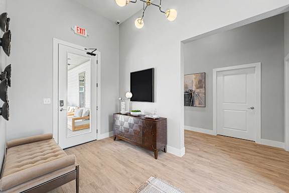 A living room with a brown leather chair, a wooden cabinet, a flat screen TV, and a white door.