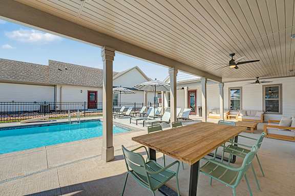 A wooden table is surrounded by chairs on a patio.