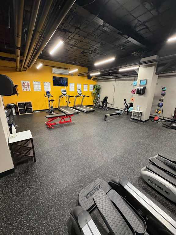 A gym with a variety of equipment including treadmills, weight machines, and exercise benches.