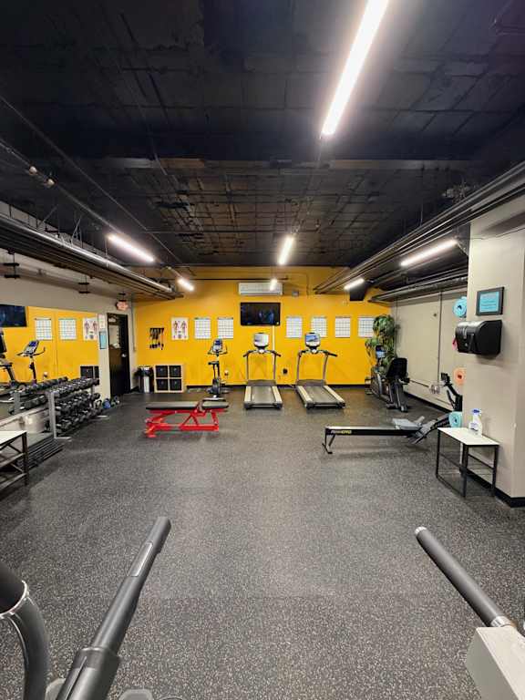 A gym with a variety of equipment including treadmills, weights, and exercise machines.