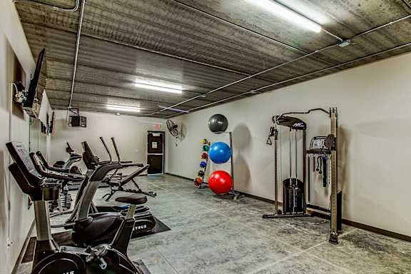 A gym with a row of treadmills and exercise balls.