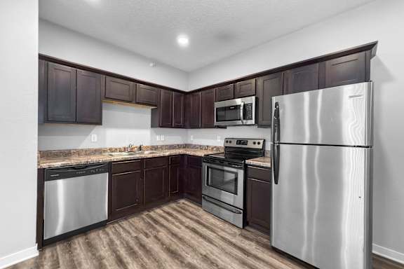 A kitchen with dark brown cabinets and stainless steel appliances.