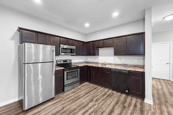 A kitchen with dark brown cabinets and a stainless steel refrigerator.