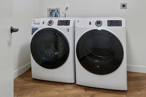 Two white front load washing machines in a laundry room.