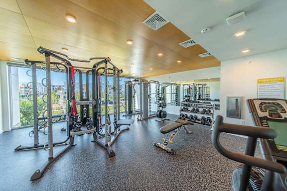 A gym with a variety of equipment including treadmills, weights, and exercise machines.