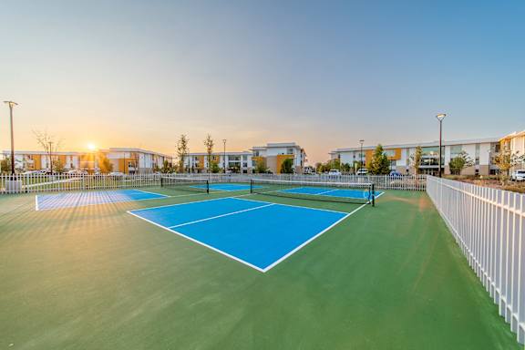 A tennis court with a blue surface and white boundary lines.