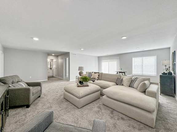 A spacious living room with a grey sofa set and a grey rug.