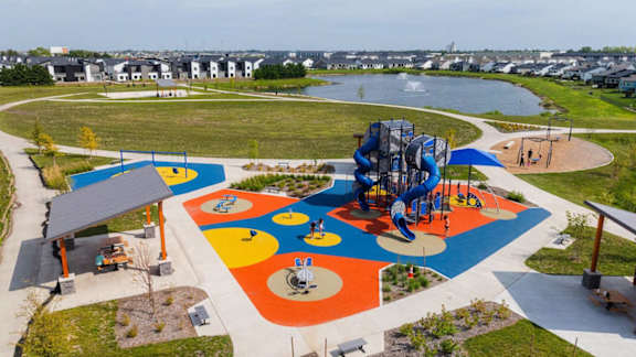 A playground with a blue and yellow slide and a red and white slide.