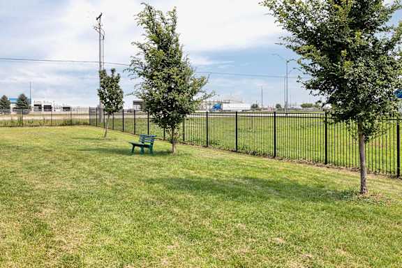 A park with a green bench and a black fence.