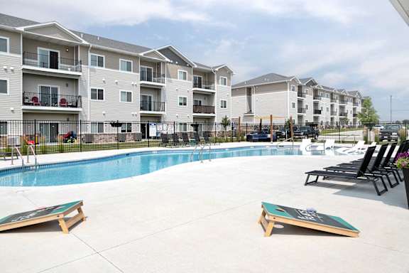 A pool area with a slide and sun loungers in front of apartment buildings.