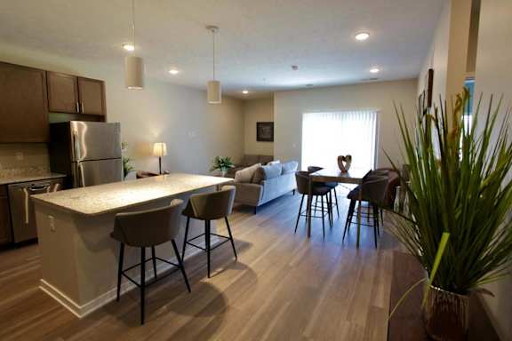 A kitchen with a bar and chairs in front of it.