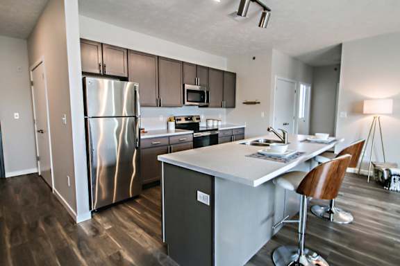 A modern kitchen with a stainless steel refrigerator and a dining table with chairs.