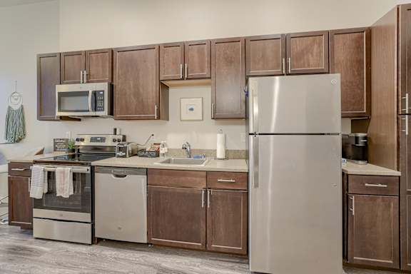 A kitchen with brown cabinets and a stainless steel refrigerator.