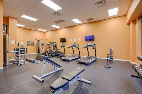 A gym with a variety of equipment including treadmills, weight machines, and benches.
