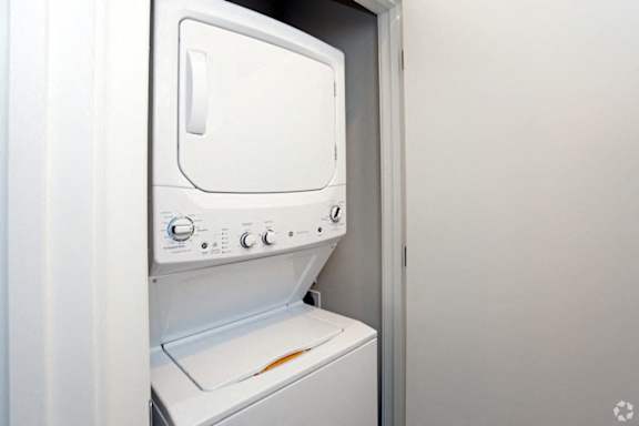 A white dryer is in a small, white-walled room.