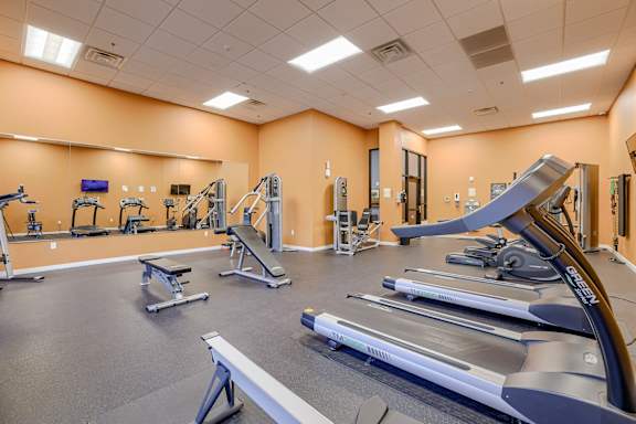 A gym with a variety of equipment including treadmills, weight machines, and benches.