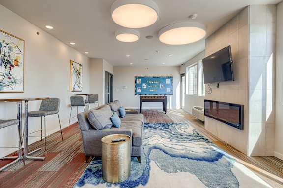A modern living room with a grey couch and a blue rug.