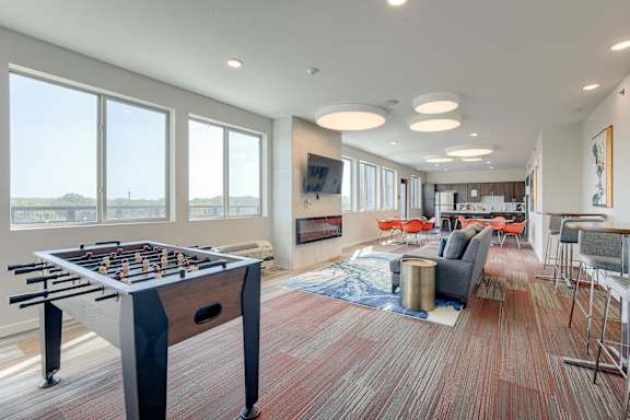 A foosball table is in the middle of a room with a red carpet.