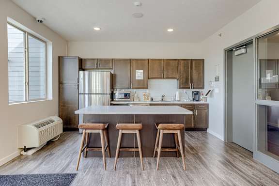 A kitchen with a white countertop and wooden bar stools.