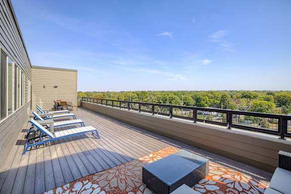 A balcony with a table and chairs overlooking a forest.