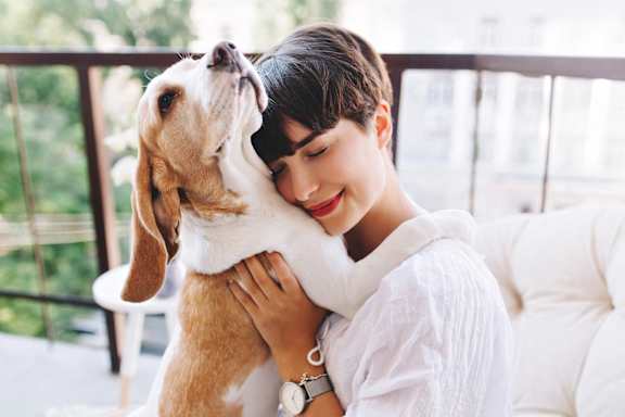 A woman is hugging a dog on a balcony.