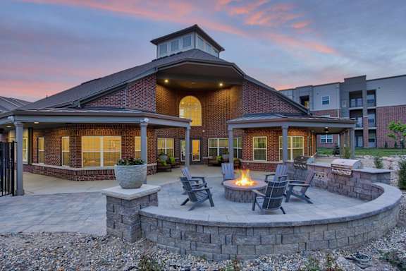 Clubhouse exterior with a patio and a fire pit at sunset.
