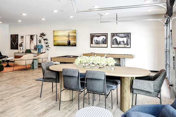 A modern dining room with a round table and grey chairs.