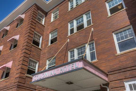 A brick building with a sign that says Colonial Hotel.