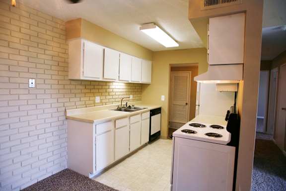 A kitchen with a white stove and white cabinets.