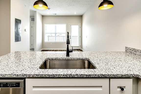 A kitchen with a granite countertop and a stainless steel sink.