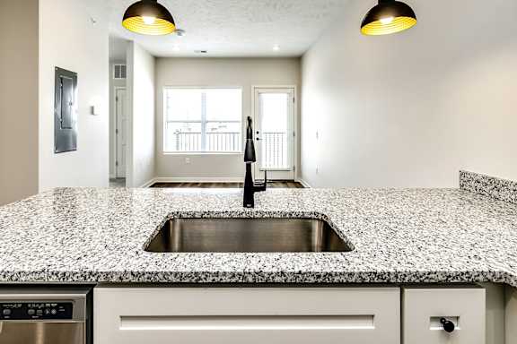 A kitchen with a granite countertop and a stainless steel sink.