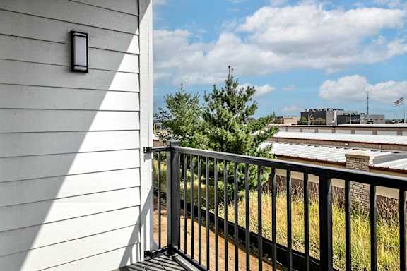 A balcony with a black railing and a white wall.