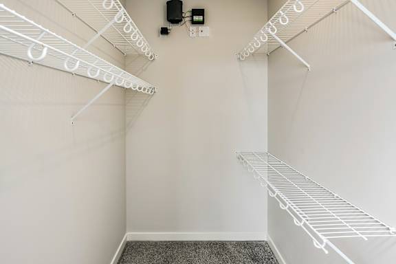 A white walk-in closet with shelves and a black speaker.