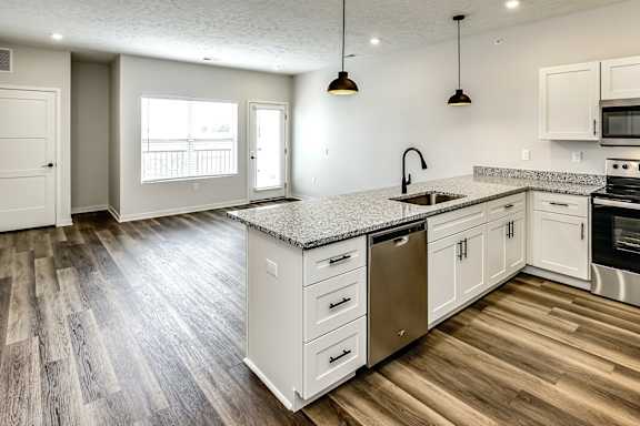 A kitchen with white cabinets and a granite countertop.