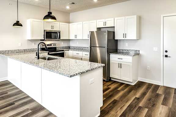 A kitchen with white cabinets and a granite countertop.