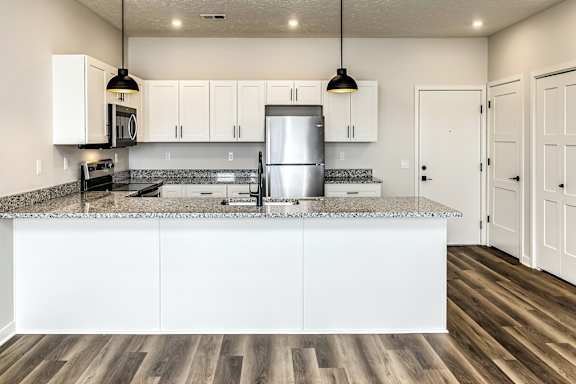 A kitchen with white cabinets and a granite countertop.