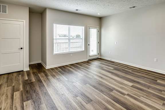 A room with wooden flooring and a window with blinds.