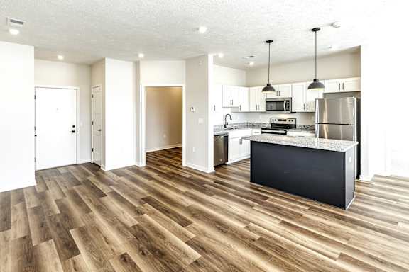 A kitchen with a refrigerator, microwave, and oven.
