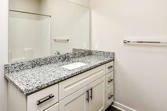 A bathroom with a granite countertop and white cabinets.