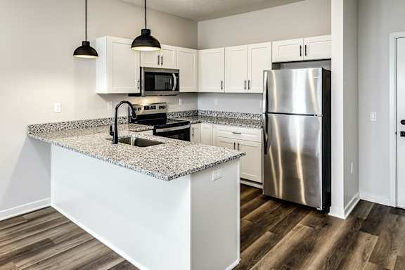 A kitchen with a granite countertop and stainless steel appliances.