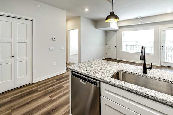 A kitchen with a granite countertop and a stainless steel dishwasher.