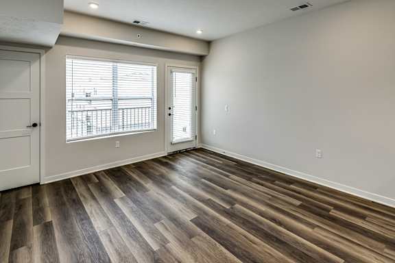 A room with wooden flooring and a window with blinds.
