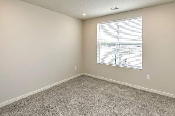 A room with a window covered by white blinds.